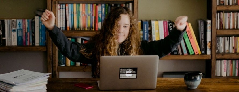 Girl at laptop in front of bookshelves